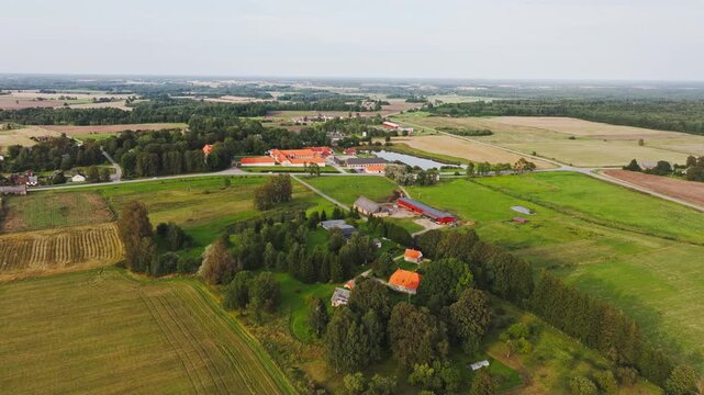 Drone footage revealing horse stable in peaceful rural landscape, fields, rees