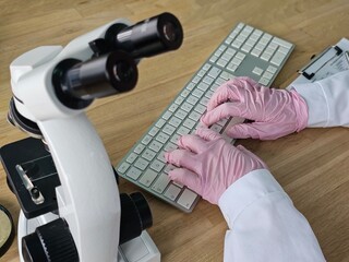 Scientist using microscope and keyboard in laboratory