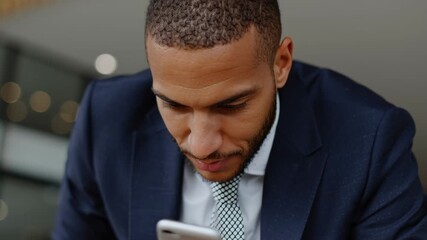 A businessman in a suit focuses on his smartphone and tablet in a sleek office. He appears engaged and attentive, balancing technology and productivity in his daily tasks - Powered by Adobe