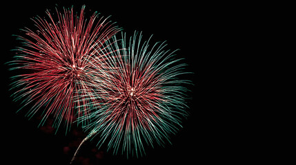 Vibrant red and green fireworks burst across a dark night sky, illuminating the celebration