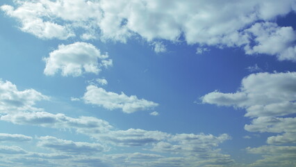 A serene and calm sky with fluffy white clouds floating gracefully across the blue horizon