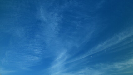 A Wide Expansive Blue Sky Filled with Wispy White Clouds and a Distant Celestial Object
