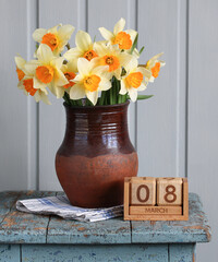 Daffodils bouquet and march 8 calendar on rustic table