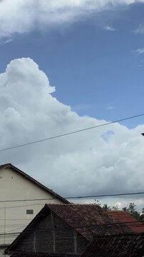 Time lapse Expansive blue sky filled with majestic cumulus clouds above residential rooftops. Time-lapse clouds vertical video