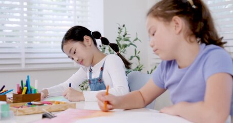 asian girl elementary student drawing with pencil during slow motion classroom education activity caucasian girl classmate works on art project teamwork friendship creativity childhood study learning - Powered by Adobe
