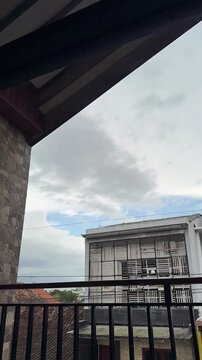 Time lapse Cloudy skies frame modern buildings seen from a balcony overlooking urban details. Vertical Time-lapse clouds video