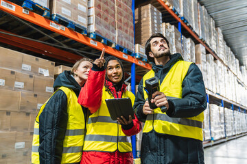 Group of diverse workers wearing warm clothing and safety vests, scanning products and discussing stock in a refrigerated warehouse