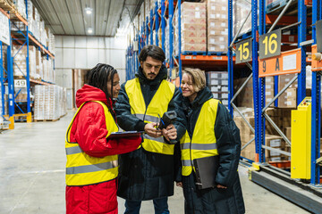 Diverse team of logistics workers scanning products in a low temperature cold storage warehouse, managing inventory with modern technology