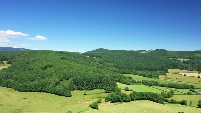 Aerial view of lush green hills, forests, and patchwork fields under a clear blue sky in the Morvan region of France. Peaceful rural landscape ideal for nature and travel concepts.