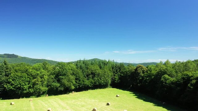 Scenic view of lush green hills and patchwork fields under a clear blue sky in the Morvan region of France. Peaceful rural landscape with vibrant summer colors.