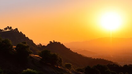 Serene Sunset Over Hills with Vibrant Orange Sky and Silhouetted Trees in Scenic Landscape View
