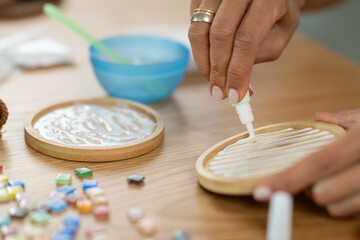 Applying glue to coaster pieces during a careful home craft session. Highlights accuracy, hand coordination, and steady creative workflow.