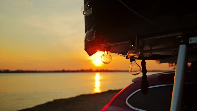 Rooftop tent, glowing string lights creating minimalist camping mood at sunset