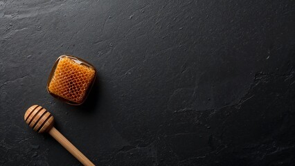 Raw Honeycomb and Dipper on Dark Stone Background with Copy Space.