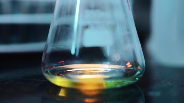 A picker is drawing out a few drops of a yellow chemical from a beaker in a lab.