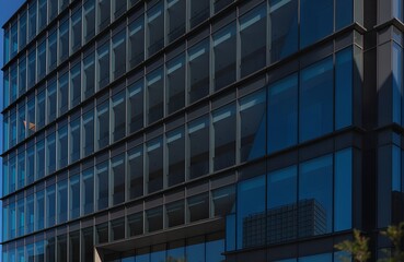 Fototapeta premium Modern Glass Office Building – Reflective Facade with Sleek Urban Architecture and Blue Sky Integration