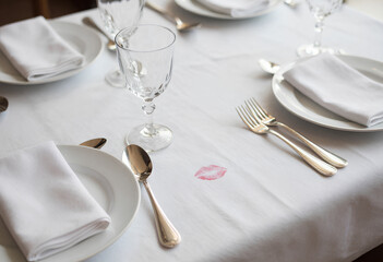 An intimate Valentine's tablescape with crisp linen, silverware, and a tell-tale lipstick mark, evoking luxury romance and sophisticated dining.