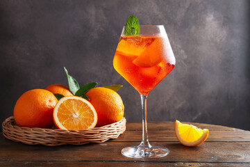 Glass of refreshing spritzer cocktail with mint and oranges on wooden table
