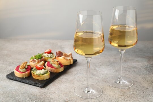 White wine in glasses and bruschette on grey table