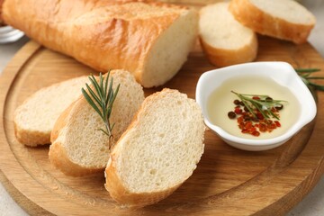 Naklejka premium Slices of baguette with olive oil, rosemary and spices on light table, closeup