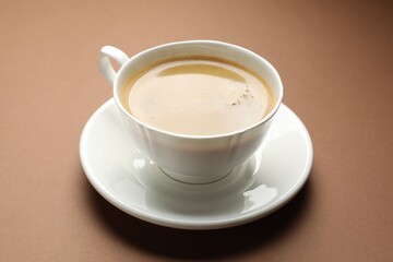 Fototapeta premium Aromatic coffee in cup on brown background, closeup