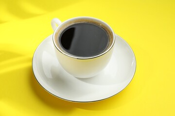 Aromatic coffee in cup on yellow table