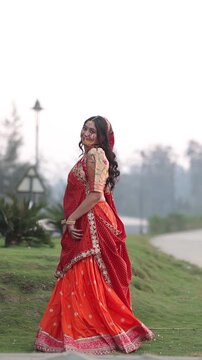Beautiful Indian woman wearing an orange traditional lehenga choli and ethnic jewelry, posing and walking gracefully in a natural forest environment. Cultural Indian fashion video showcasing heritage 