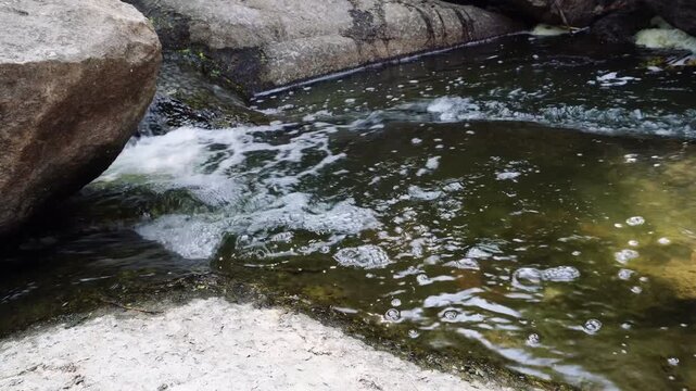 Clear stream water flowing gently around rocks creating calm natural river surface