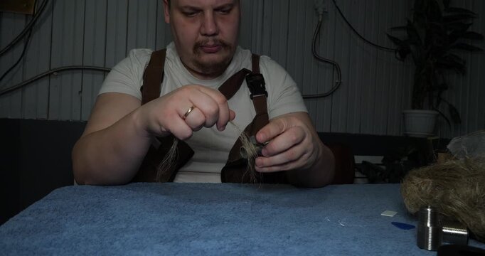 A professional plumber wraps the threads of a metal fitting with tow to ensure a watertight connection. The plumber carefully prepares the plumbing equipment for installation or repair.