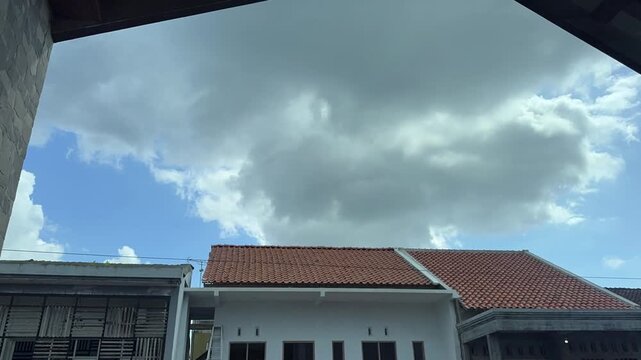 Time lapse A view of a cloudy sky above a row of residential rooftops on a bright day. Time-lapse clouds video