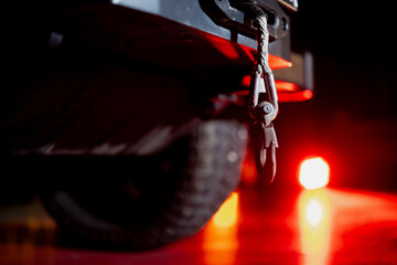 Heavy duty towing hook and cable mounted on vehicle rear with rugged tire and red warning light glow, industrial transport safety concept