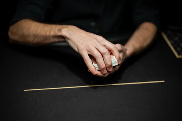 Professional poker dealer preparing card deck by hand on casino table felt, focused on secure card control during live regulated gambling session