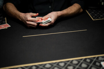 Professional poker dealer holding playing cards during live casino game, focused on secure card handling and procedural control at poker table