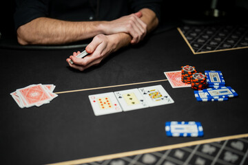 Professional casino poker game in progress with visible community cards, dealer control, and player betting actions on regulated gaming table