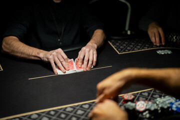 Live casino poker table scene with dealer hands separating card deck at betting line while players wait, showing controlled gaming industry procedures