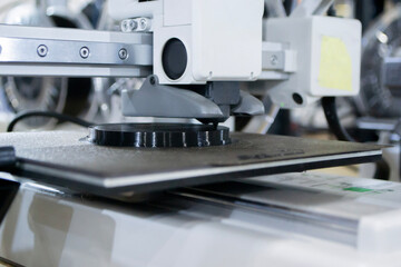 3D printer close up. Working 3D printer in process of printing object from molten black plastic. 3D printer creating model by flowing liquid plastic from extruder of printer. 3D printing technology