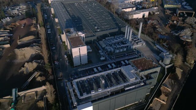 Large modern industrial complex, housing data center and telecommunication structures, showing extensive rooftop cooling systems. Smooth aerial view top down drone view