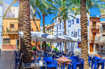 Fototapeta premium Old town Calpe city historical centre with street restaurant outdoor cafe on square Plaza Espana, houses colorful traditional buildings in sunny day, Calp Casco Antiguo, Valencian Community, Spain