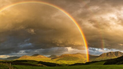 Vibrant rainbow arcing across landscape after storm, green fields or mountains, dramatic sky, professional nature photography, natural phenomenon, commercial quality, hope and beauty, weather event, c
