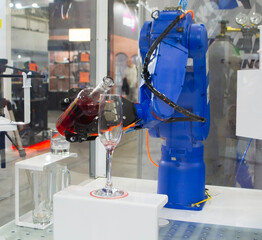 Robotic manipulators. Robot pouring liquid drink from bottle into glass. Industrial robot. Robot arm hand. Industrial manipulators for variety welding, material handling, palletizing. Robotization