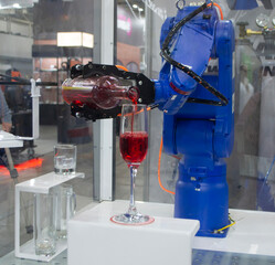 Robotic manipulators. Robot pouring liquid drink from bottle into glass. Industrial robot. Robot arm hand. Industrial manipulators for variety welding, material handling, palletizing. Robotization