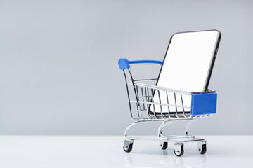 Mobile Phone in Shopping Cart - E-commerce and Online Payment Concept