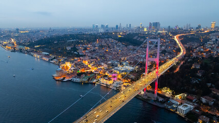 Naklejka premium A breathtaking aerial night view of Istanbul showcasing the illuminated 15 July Martyrs Bridge (Bosphorus Bridge) stretching across the Bosphorus Strait. The city glows.