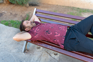 Latin American man napping on park bench, enjoying outdoor leisure and relaxation