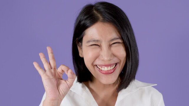 Smiling Woman Making OK Hand Gesture on Purple Background
