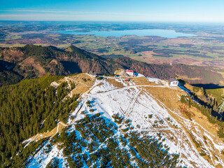 Top view to the Hochfelln mountain peak and the summit cross with a stunning landscape down to the valley of the Bavarian Chiemgau