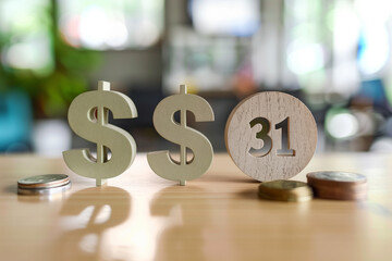 Wooden letters G, number 1, and a dollar sign on a wooden surface with a blurred plant background