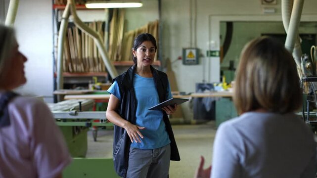 Female carpentry instructor teaching a group of students in a workshop
