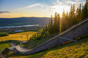 Scenic sunset view of Lillehammer, Norway, from the ski jumping arena overlooking Lake Mjosa and surrounding landscape.