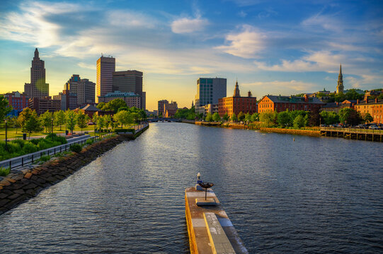 Sunset view of downtown Providence and the Providence River in Rhode Island, USA, with city buildings and New England riverside greenery.